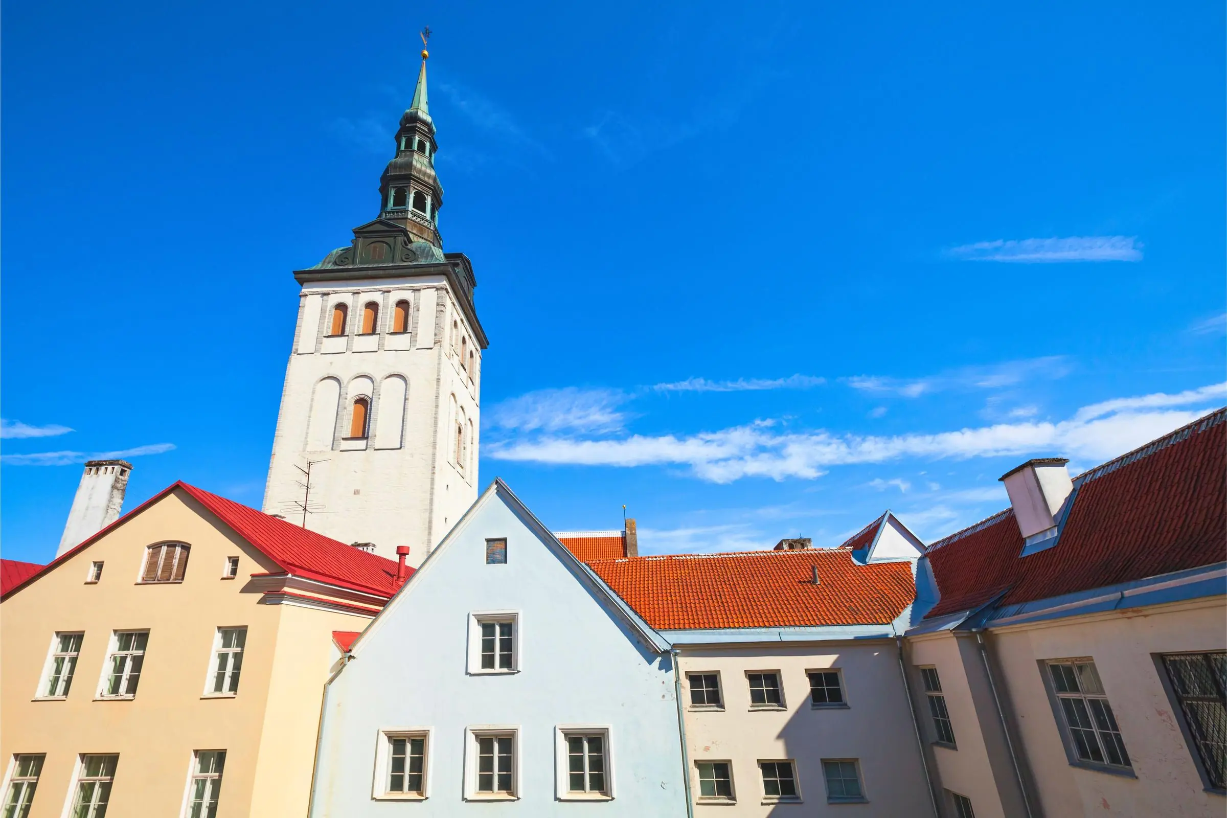 The towering spire of St. Nicholas Church against the Tallinn Old Town skyline